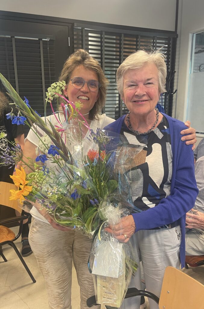 Voorzitter Joyce en erelid Anja. Anja houdt een bos bloemen vast.